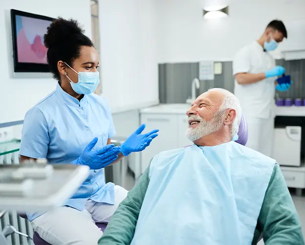 Older male patient talking to female dentist