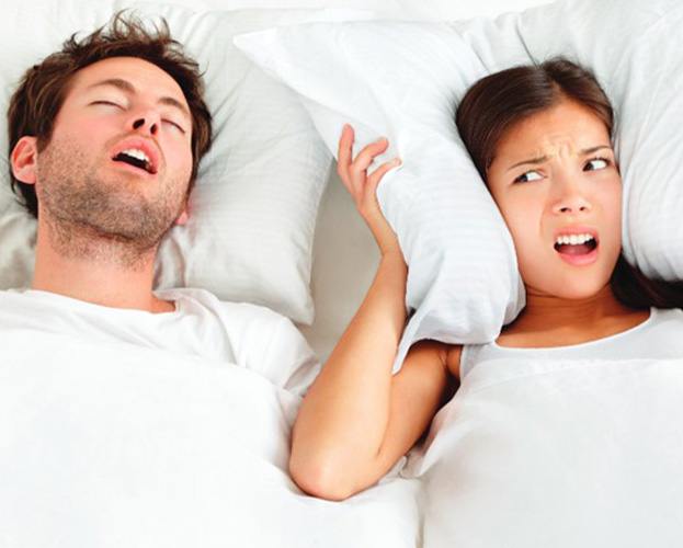 Woman covering her ears as her husband snores